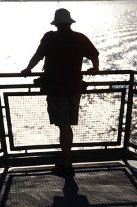 Rear view of silhouette man standing against railing