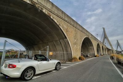 Cars on bridge against sky in city