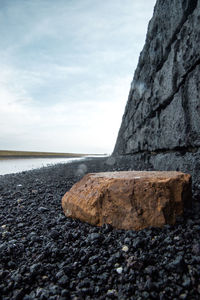 Stone wall by sea against sky