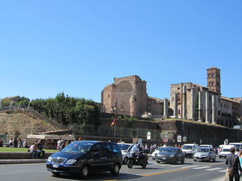 Cars on road in city against clear sky