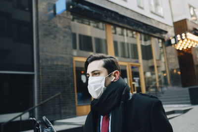 Portrait of young man standing on street in city