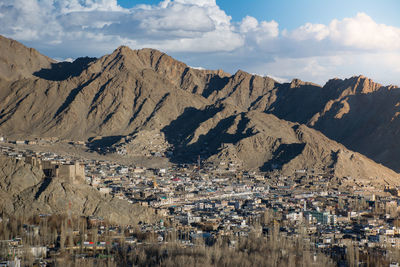 Aerial view of town by mountains against sky