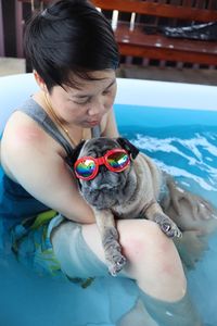 Woman with dog sitting in wading pool