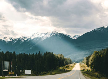 Road leading towards snowcapped mountains against sky