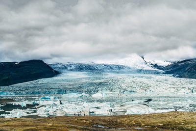 Scenic view of ice glacier against cloudy sky