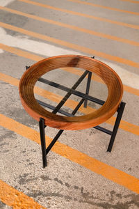 Double table in brown wood, with circular metal edges and several glass shelves.