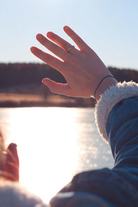 Close-up of hand against sky during winter