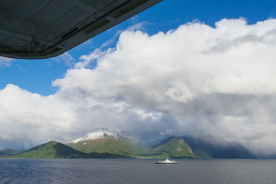 Scenic view of sea by mountains against sky