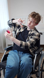 Young man sitting on wheelchair while vlogging at home
