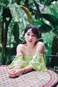 Portrait of young woman sitting on table