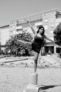 Young woman exercising on concrete pole against building