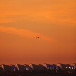 Low angle view of airplane flying in sky during sunset