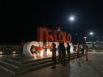 People on illuminated street in city at night