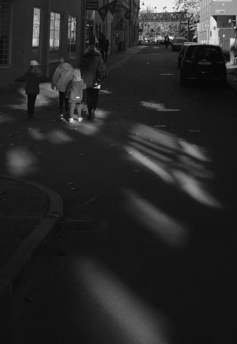 transportation, street, car, city, land vehicle, mode of transport, city life, building exterior, city street, road, walking, road marking, incidental people, architecture, zebra crossing, men, built structure, on the move, person