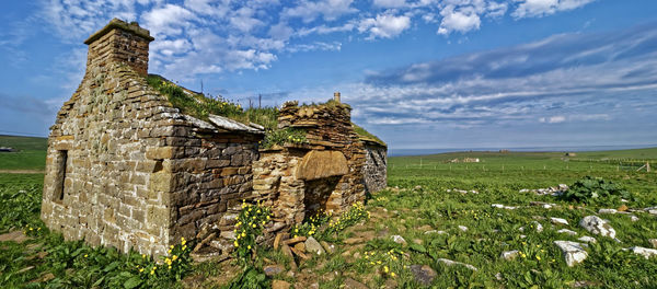 Stone wall on field against sky