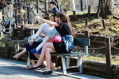 Rear view of mother and daughter sitting outdoors
