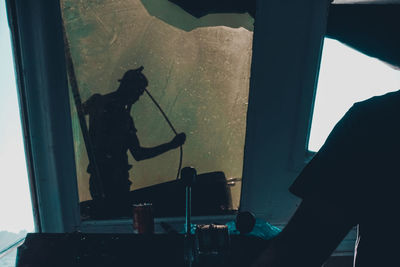 Silhouette man working on window