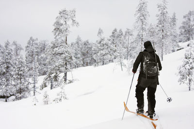 Rear view of person skiing on snow covered mountain