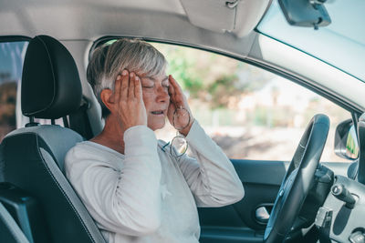 Frustrated senior woman sitting in car