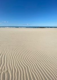 Sand dunes in desert against blue sky