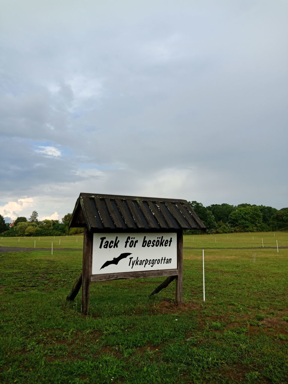 text, communication, cloud - sky, sky, western script, sign, grass, field, plant, land, nature, day, no people, information, environment, landscape, green color, information sign, outdoors, tranquility