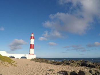 Lighthouse on beach against sky