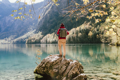 Man standing on rock by lake against mountain