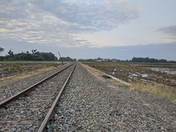 Railroad tracks on field against sky