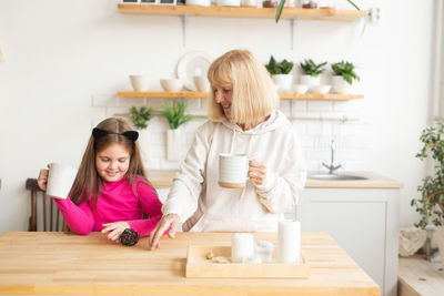 Portrait of smiling family sitting on table at home