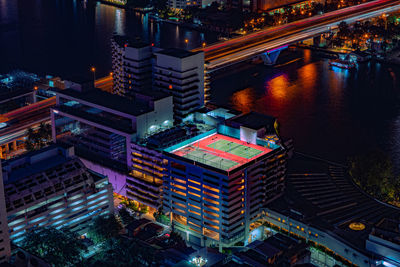 High angle view of illuminated buildings at night. the tennis court on rooftop building