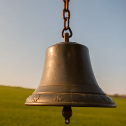 Close-up of metal chain hanging on field against sky