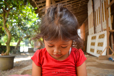 Close-up of girl looking down while sitting on sidewalk