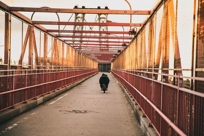 Rear view of man walking on footbridge