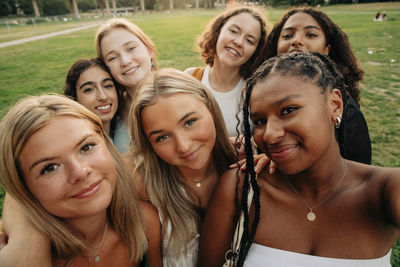 Smiling multiracial teenage girl taking selfie at park