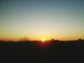 Scenic view of silhouette field against sky during sunset