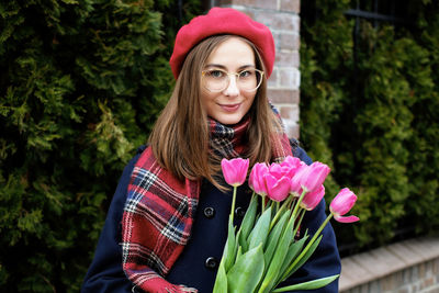 Young french millennial girl in beret and coat with tulips in hands