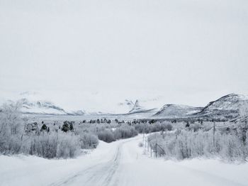 Road amidst snow covered landscape against sky