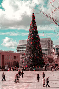 People on christmas tree against buildings in city