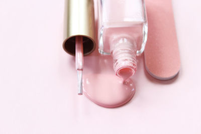 High angle view of nail polish with file on pink background