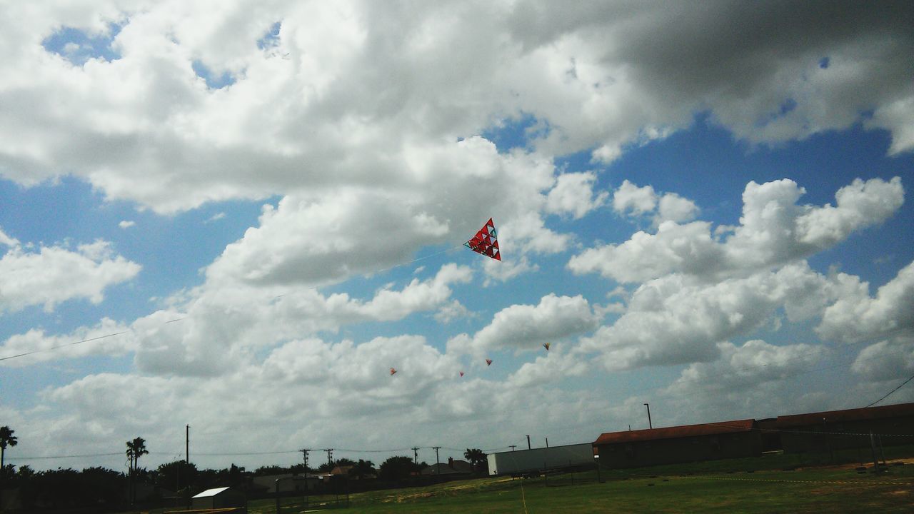 sky, cloud - sky, transportation, cloudy, cloud, flying, landscape, low angle view, mode of transport, nature, tranquility, day, mid-air, weather, scenics, airplane, tranquil scene, beauty in nature, flag, field