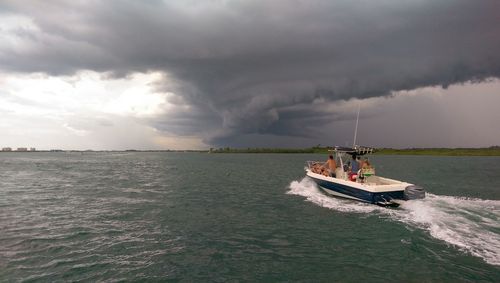 Boat in sea against cloudy sky