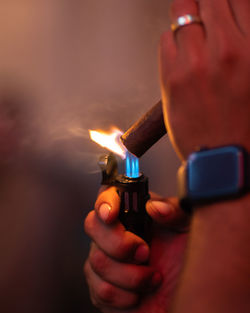 Cropped hand holding a torch lighter lighting a cigar