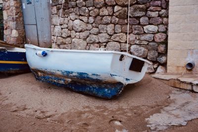 Abandoned boat moored on wall