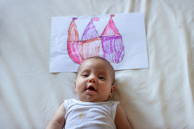 Portrait of lying on the bed baby with crown painted on the paper