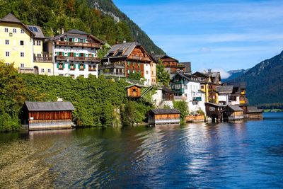 Buildings by river against sky