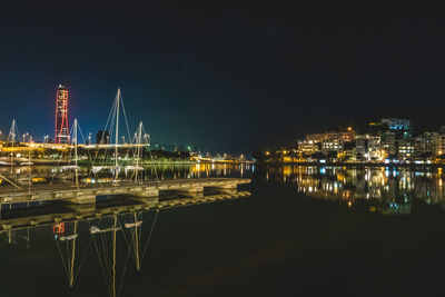 Illuminated harbor by river against sky at night