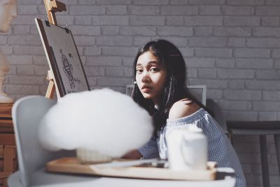 Portrait of young woman sitting on table