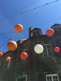 Low angle view of lanterns hanging by building against sky