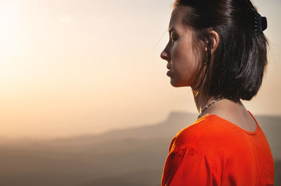 Backlit profile of a woman breathing deep fresh mountain air at morning sunrise or sunset. calm