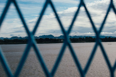 Shadow of chainlink fence on landscape against sky